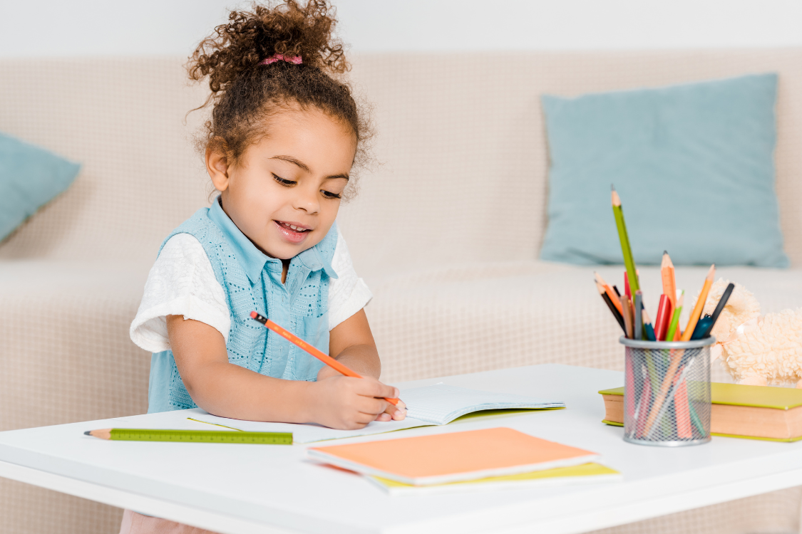 young girl with curly hair holding a pencil learning to write