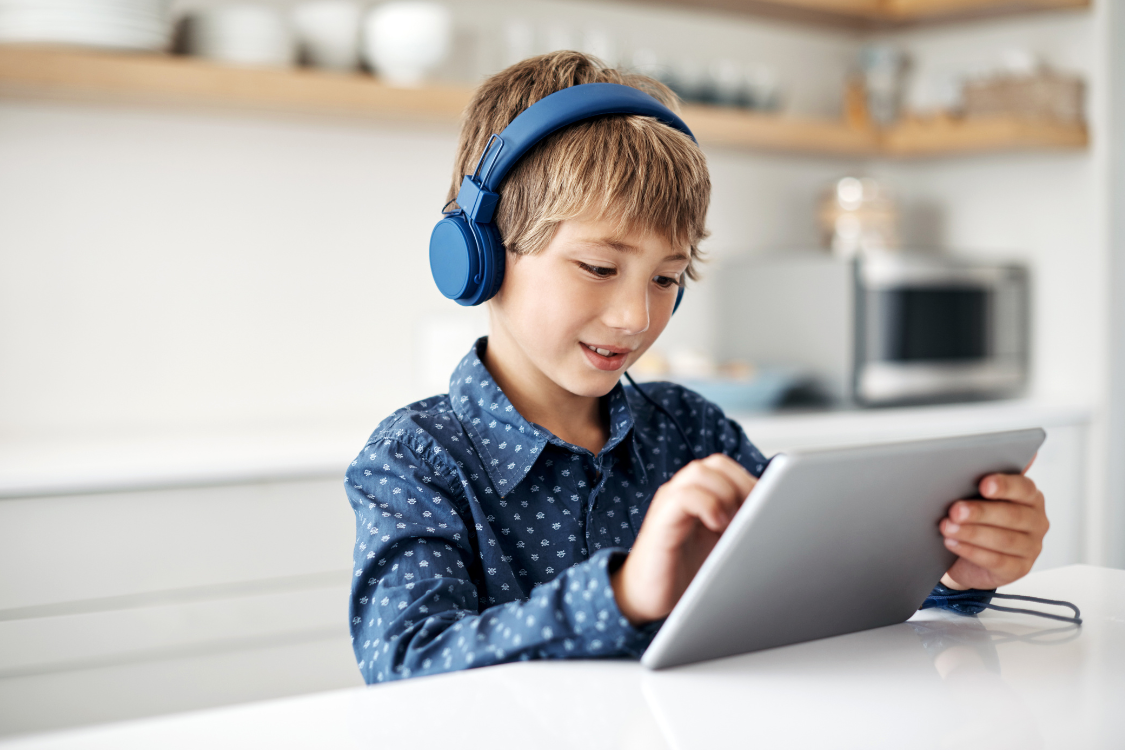 child reading with headphones on a tablet