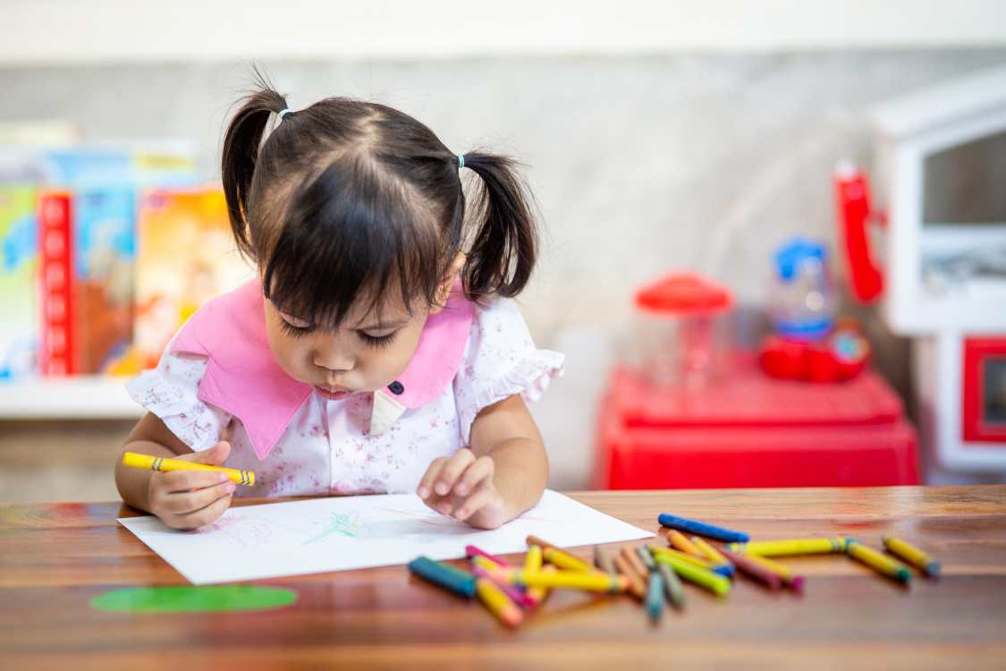 young girl writing with a crayon